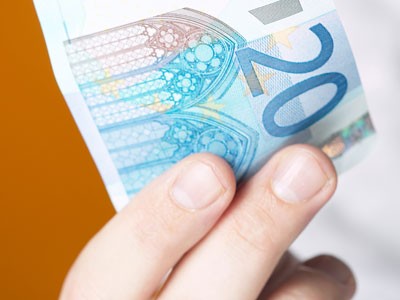 Ein hält einen 20-Euro-Schein in der Hand.